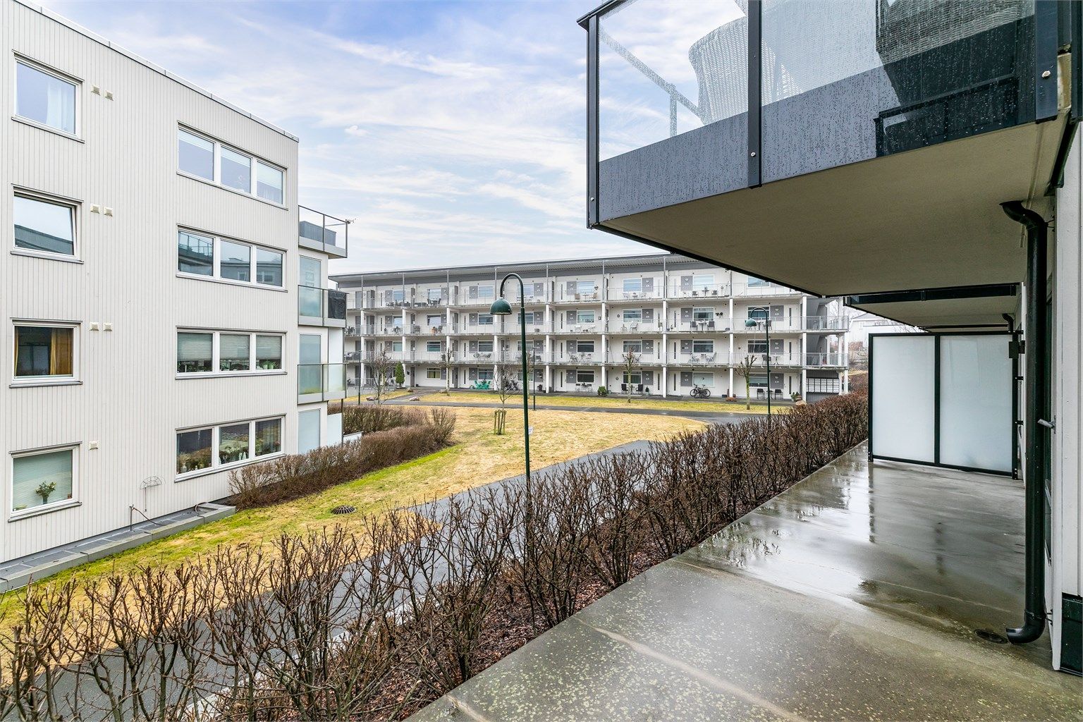 Terrassens overbyggede del er lun og et fint sted å sitte ute på lyse sommerkvelder. Hekken foran fylles med grønne blader.