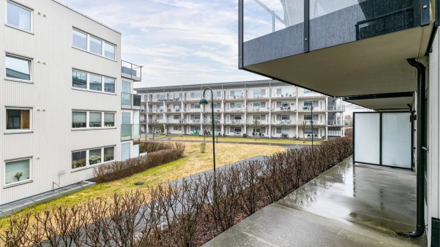 Terrassens overbyggede del er lun og et fint sted å sitte ute på lyse sommerkvelder. Hekken foran fylles med grønne blader.