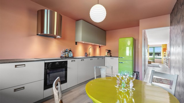 KVIK kjøkkeninnredning fra 2023 med glatte fronter og benkeplate med laminert overflate. Ventilator i børstet messing fra Røroshetta med integrert komfyrvakt.