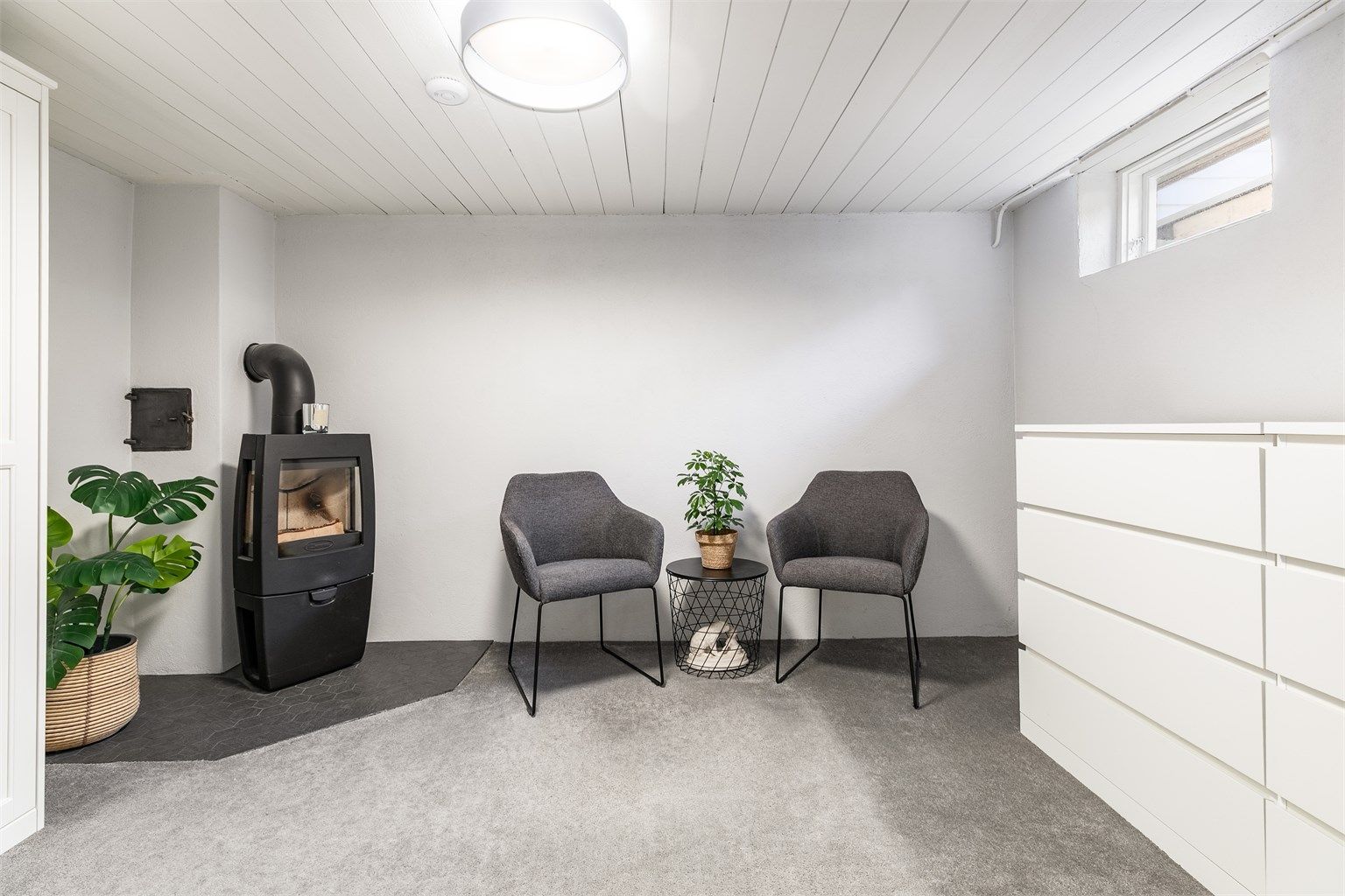 Rommet innenfor badet benyttes som stue, men er ikke omsøkt bruksendret eller godkjent for varig opphold. Vedovn ble montert i 2018, teppe og fliser ble samtidig lagt på gulvet.