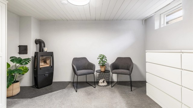 Rommet innenfor badet benyttes som stue, men er ikke omsøkt bruksendret eller godkjent for varig opphold. Vedovn ble montert i 2018, teppe og fliser ble samtidig lagt på gulvet.