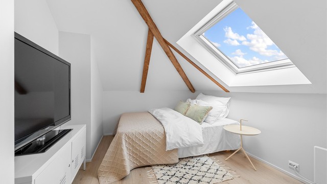 Rommet har plass til seng og oppbevaringsløsninger, med et takvindu som gir naturlig lys.