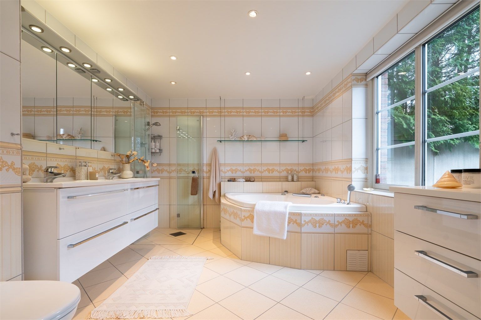 Romlig, flislagt bad med gulvvarme. Innredet med vegghengt servantskap med ovenpåliggende dobbeltvask, egen dusjnisje og innmurt boblebadekar.