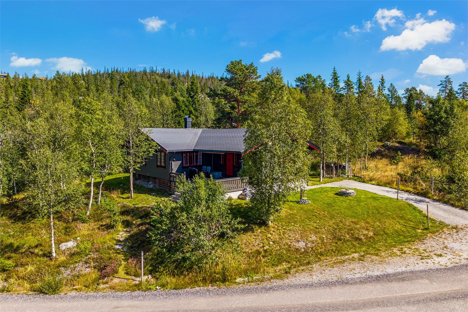 Tomten er opparbeidet med gruslagt innkjørsel på fremsiden av hytta, med plass til parkering for flere biler. 