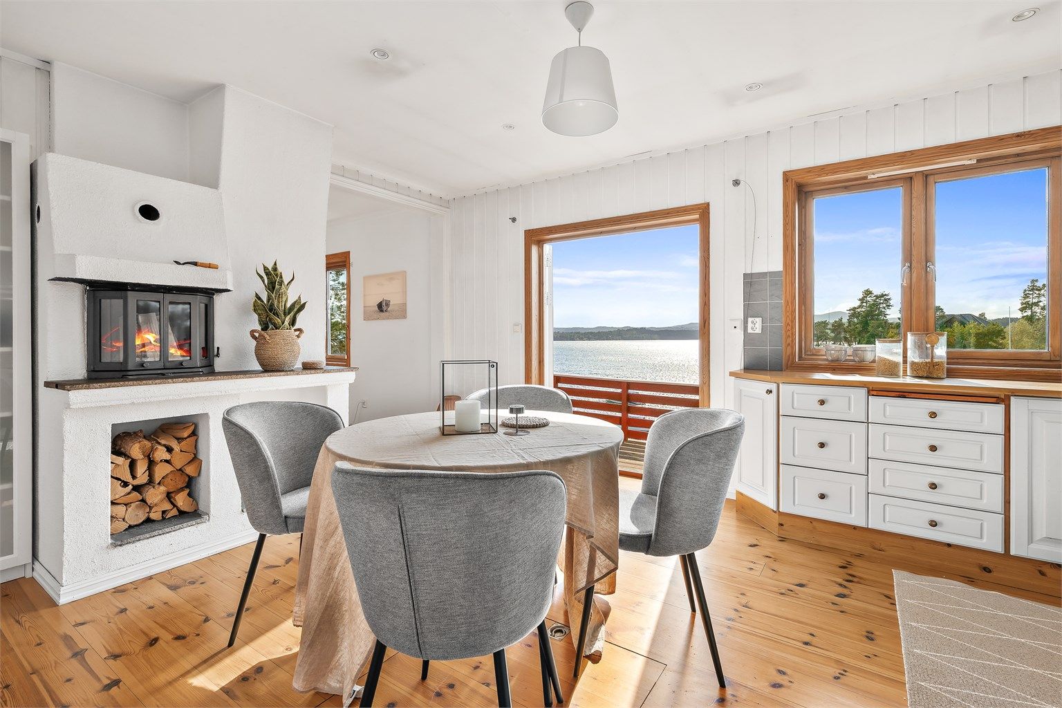 Stort kjøkken med peis og dører som åpnes mot fjorden. 