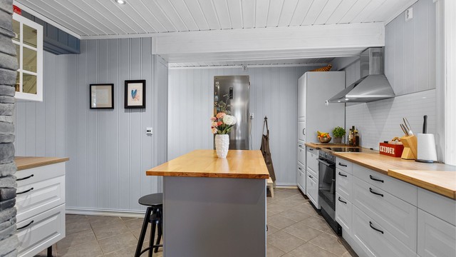 Pent kjøkken med innredning med profilerte fronter og laminert benkeplate. Flislagt gulv med varme.