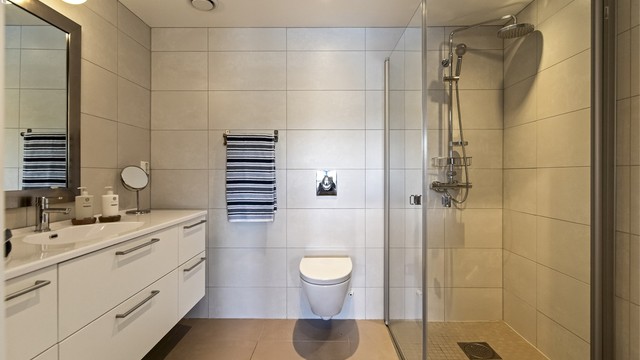 Hovedbadet, har adkomst fra hovedsoverommet, er romslig med flislagt gulv med varme, downlights i taket og vegghengt toalett.