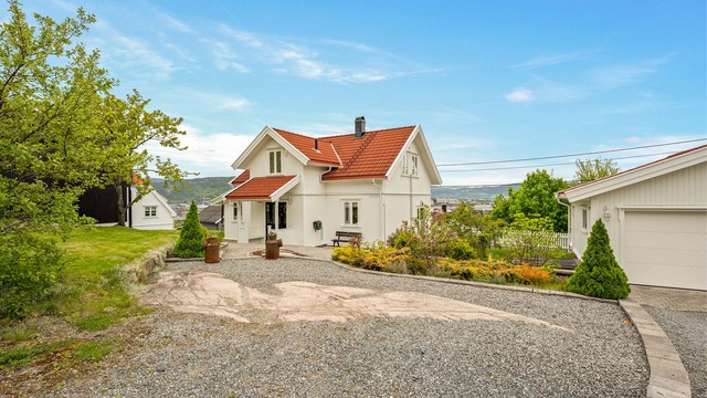Gruset parkering foran garasjen og på parkeringsområde ved siden av.