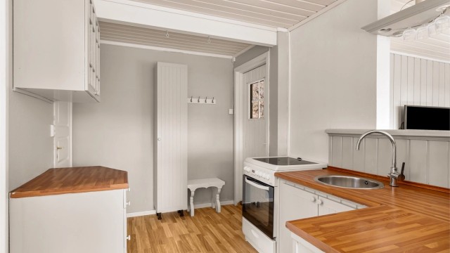 Kjøkken med åpen løsning mot stua og utgang til liten terrasse bak hytta.