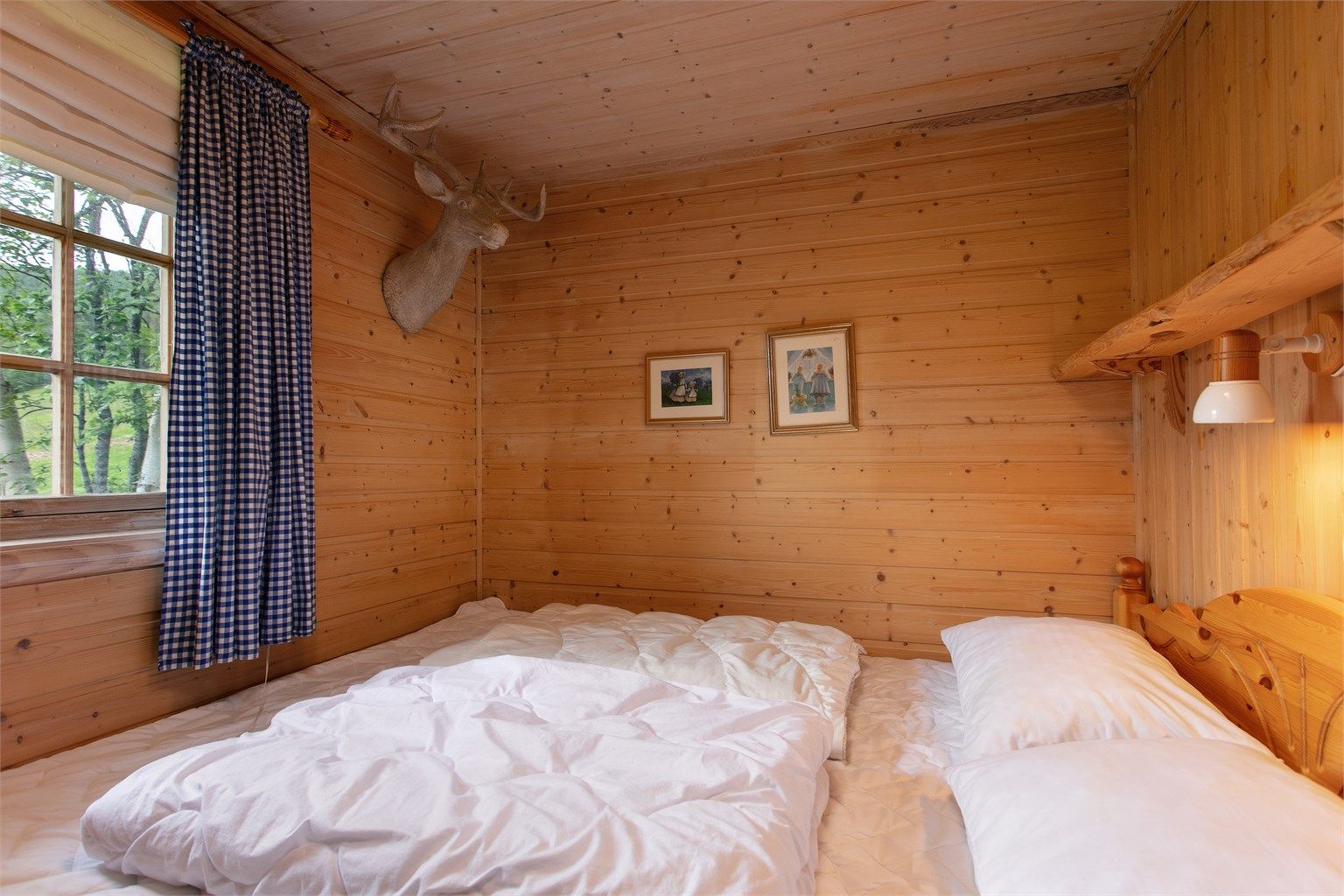 Ett av hyttas to soverom i hovedetasjen, med vegger og tak i trepanel.