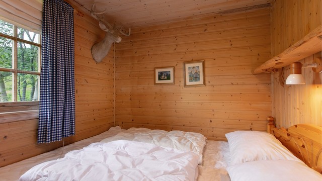 Ett av hyttas to soverom i hovedetasjen, med vegger og tak i trepanel.