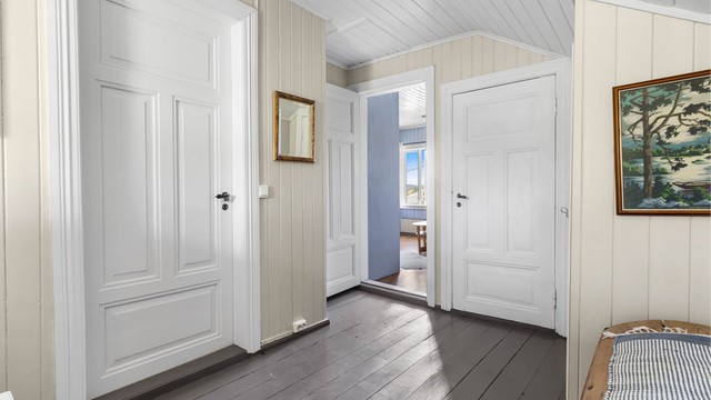 Gangen i loftsetasjen har malte panelvegger og heltre innerdører.