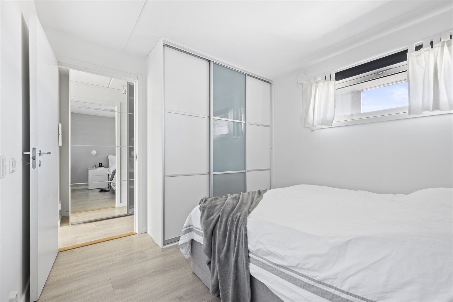 Skyvedørsgarderobe med plass til klær. Laminat på gulv