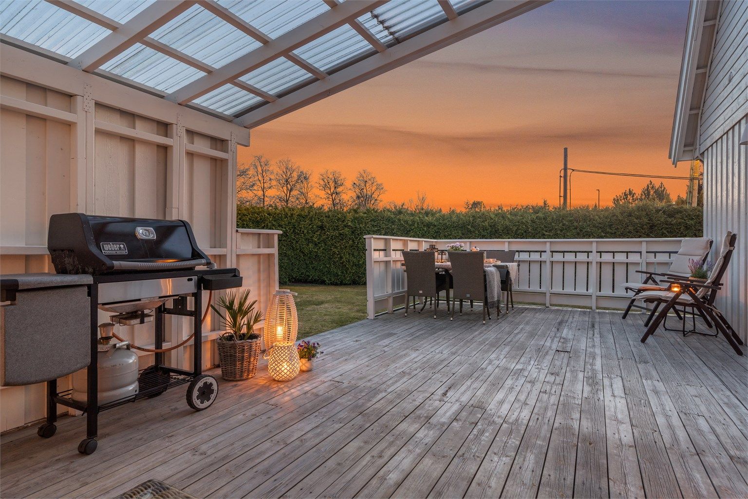 Stor, solrik og delvis overbygget  terrasse med adkomst videre til en flat og velstelt hage