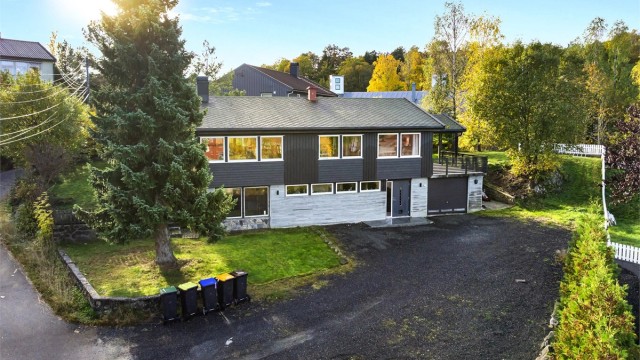 Gruset innkjørsel foran huset med god plass til parkering for flere biler.