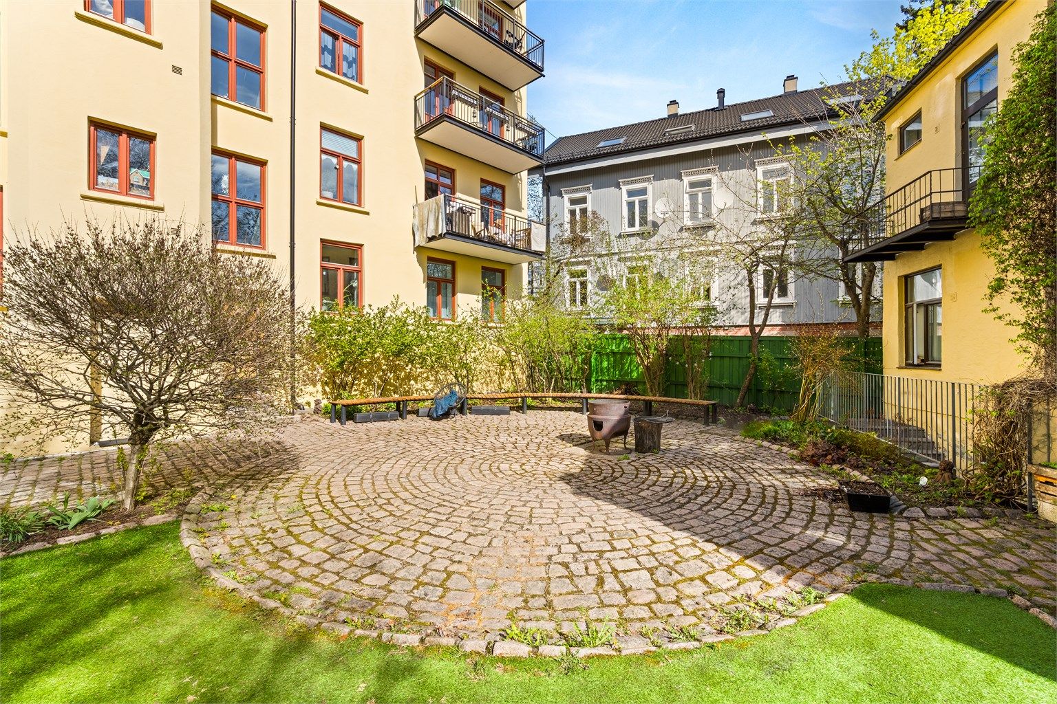 Fellesarealene er pent opparbeidet med en kombinasjon av steinbelagte soner og gressplen.