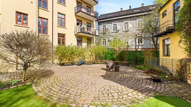 Fellesarealene er pent opparbeidet med en kombinasjon av steinbelagte soner og gressplen.