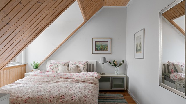 Sjarmerende soverom med skråtak og god plass til dobbeltseng med tilhørende møblement.