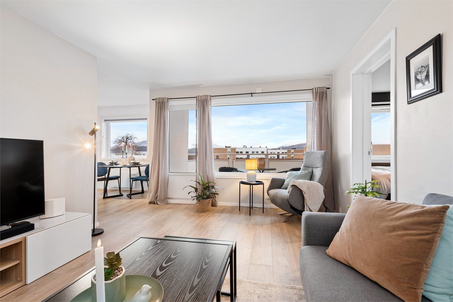 Stue og kjøkken i dels åpen løsning med lyse overflater og godt med naturlig lysinnslipp fra vinduer