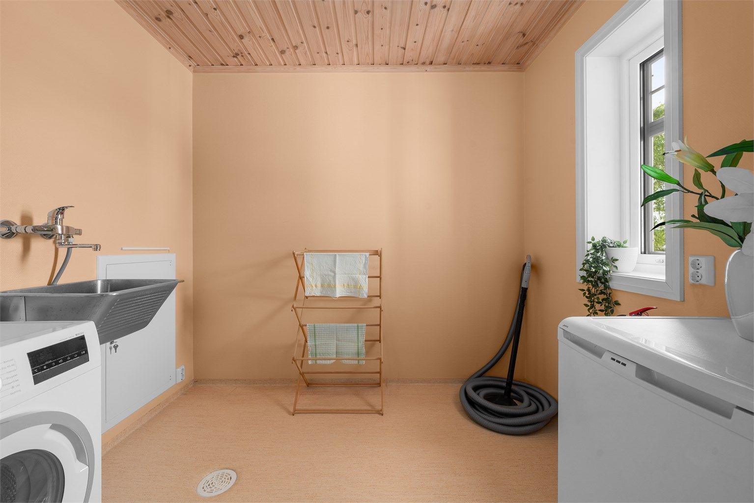 Praktisk vaskerom med gulvbelegg, gulvvarme, utslagsvask og opplegg for vaskemaskin.