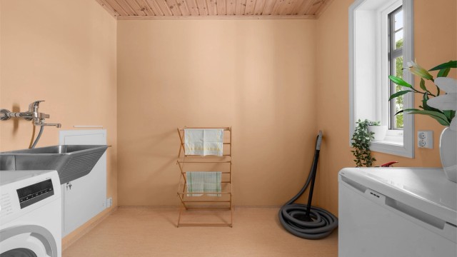 Praktisk vaskerom med gulvbelegg, gulvvarme, utslagsvask og opplegg for vaskemaskin.