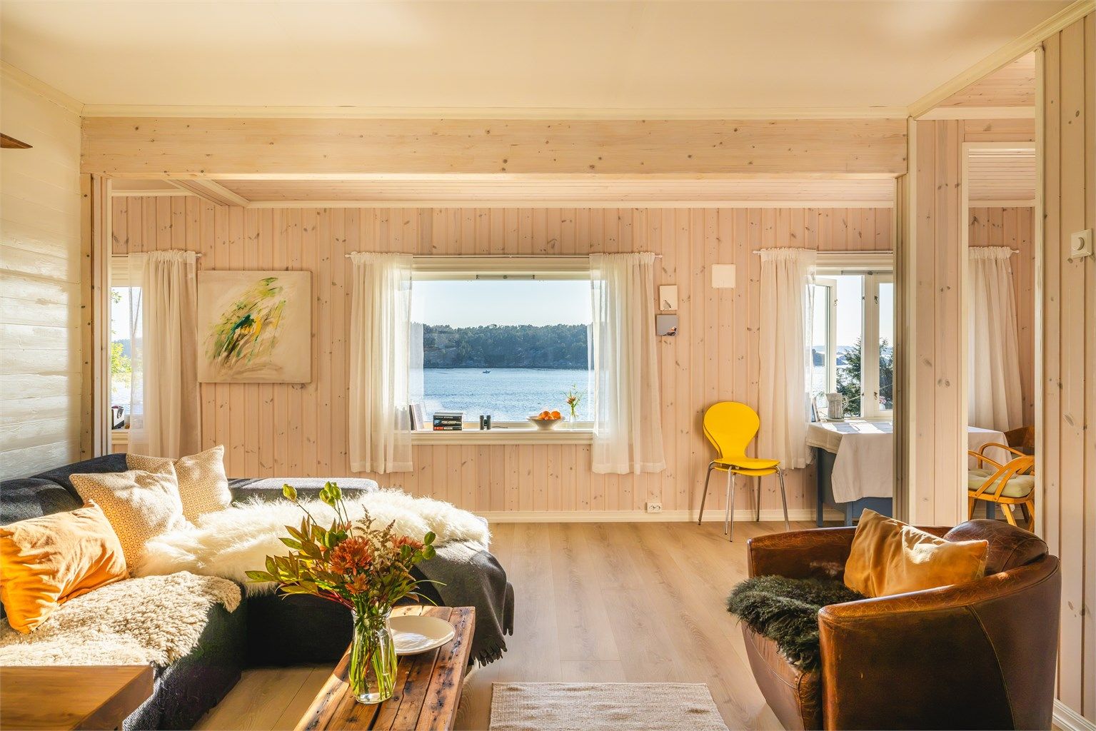 Lys stue med vedovn og store vindusflater som rammer inn sjøutsikten mot Hauglandsosen.
Foto: [Fotograf eller fotofirma]