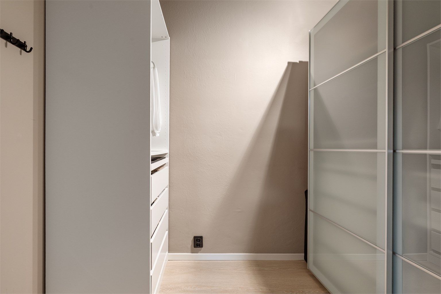 Rommet har en skyvedørsgarderobe og et åpent garderobeskap.