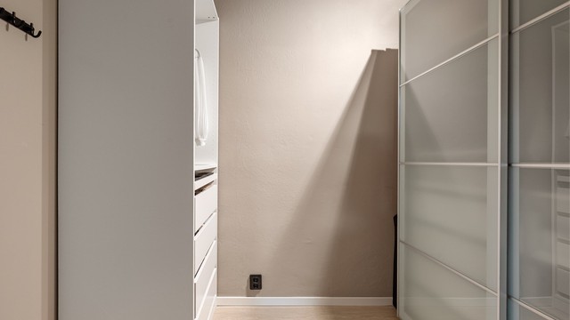 Rommet har en skyvedørsgarderobe og et åpent garderobeskap.