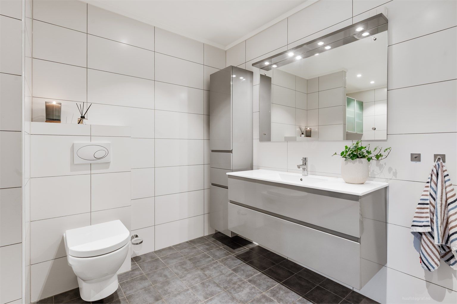 Badet er utstyrt med dusjkabinett med regnfallsdusj og vegghengt toalett.