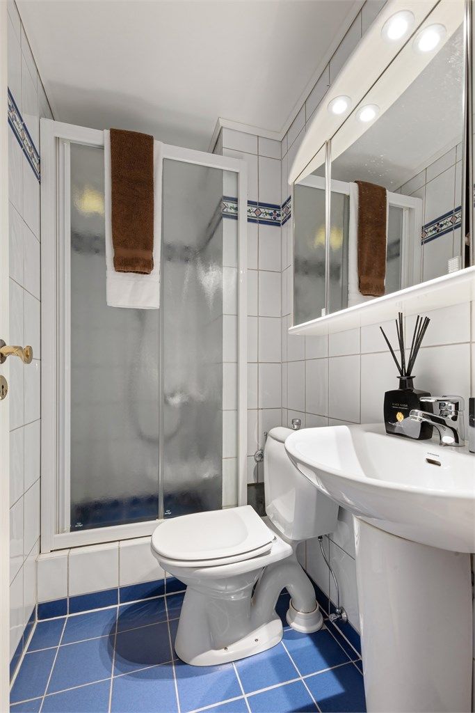 Det mindre badet har dusjhjørne med skyvedør
