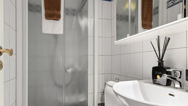 Det mindre badet har dusjhjørne med skyvedør