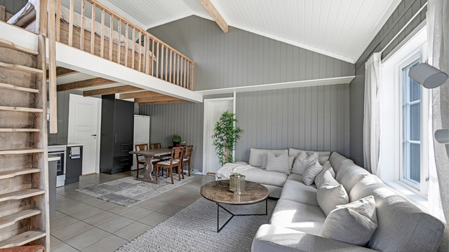 Stuen i stallbygningens innredede del har åpen løsning mot kjøkkenet og en trapp opp til hemsen. (Ikke godkjent til varig opphold / ikke godkjent som egen boenhet)