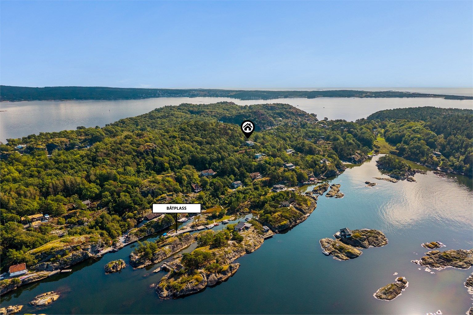 Oversiktsbilde som viser hyttas plassering og den lune båthavna nednefor. Rett ned for hytta ligger en lagune med en nydelig sandstrand.