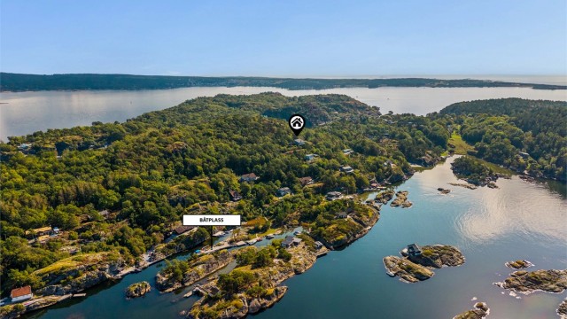 Oversiktsbilde som viser hyttas plassering og den lune båthavna nednefor. Rett ned for hytta ligger en lagune med en nydelig sandstrand.