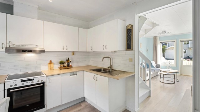 Kjøkkenet er utstyrt med komfyr med platetopp, ventilator i overskap, oppvaskmaskin under benkeplate og kjøleskap med fryserdel i nisje