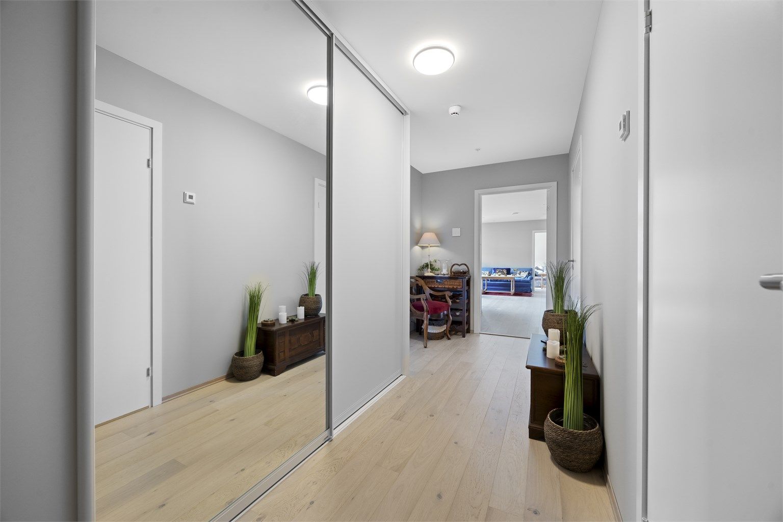 Romslig entré med skyvedørsgarderobe og laminatgulv.