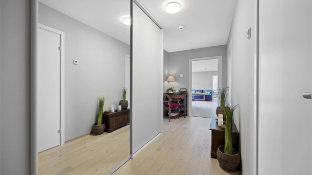 Romslig entré med skyvedørsgarderobe og laminatgulv.