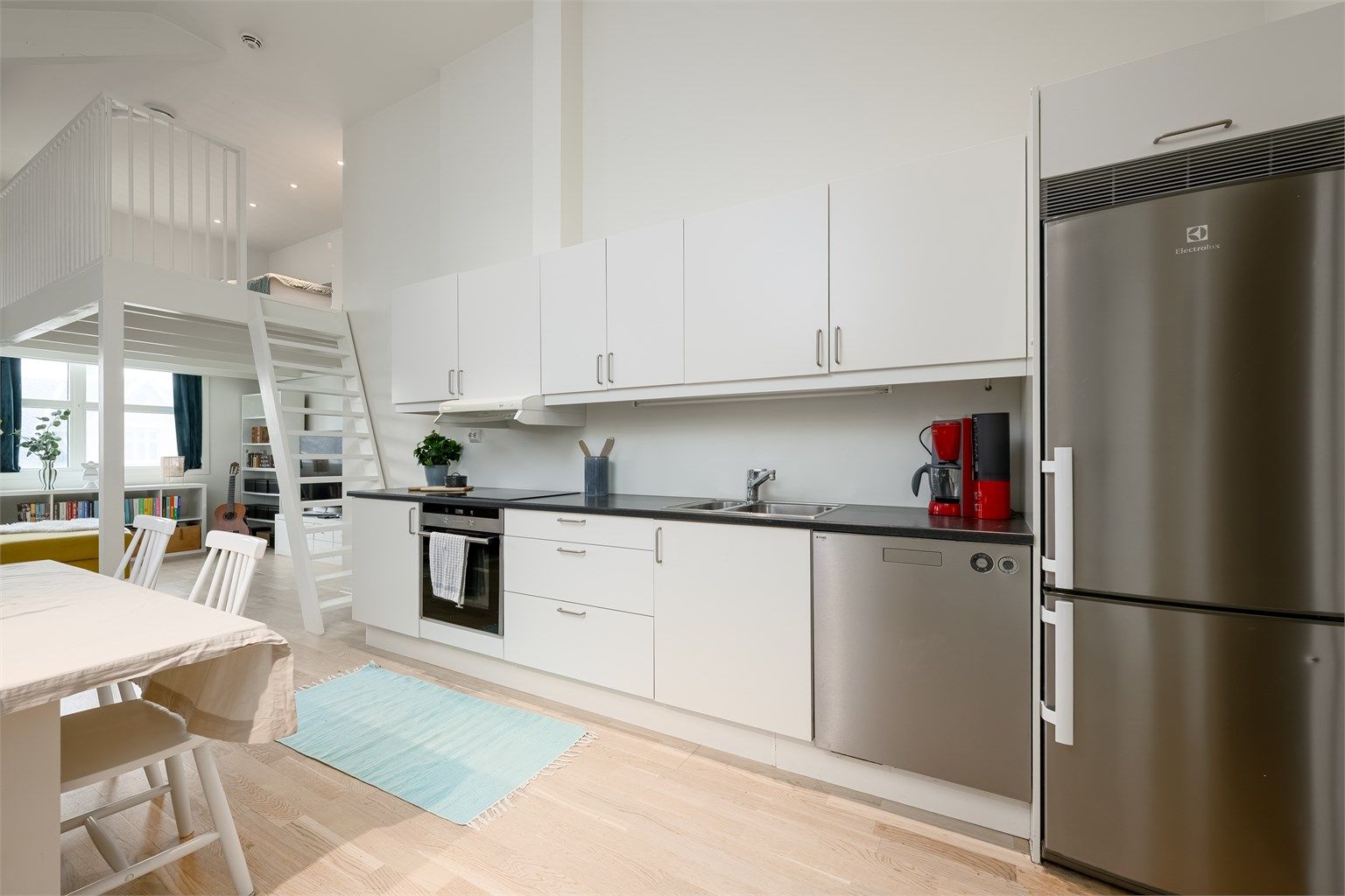 Leiligheten har en åpen og sosial planløsning mellom stue og kjøkken, med en takhøyde som gir en luftig romfølelse.