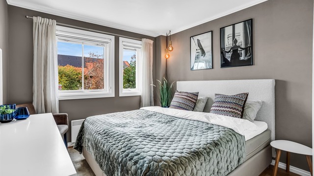 Lyst soverom med plass til dobbeltseng og nattbord.