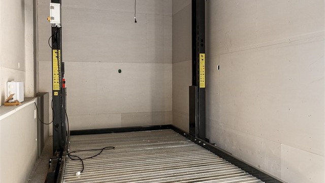 Integrert i huset er det etablert garasje for en bil, samt løfteplattform som kan heise ekstra bil (evt. oppbevaring) opp under taket.
Ny elektrisk garasjeport i 2026. Det er også lagt trekkerør til garasjen for evt. etablering av elbillader