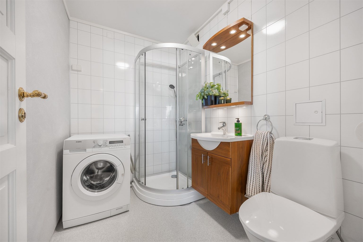 Bad i første etasje med dusjkabinett, toalett og opplegg for vaskemaskin.