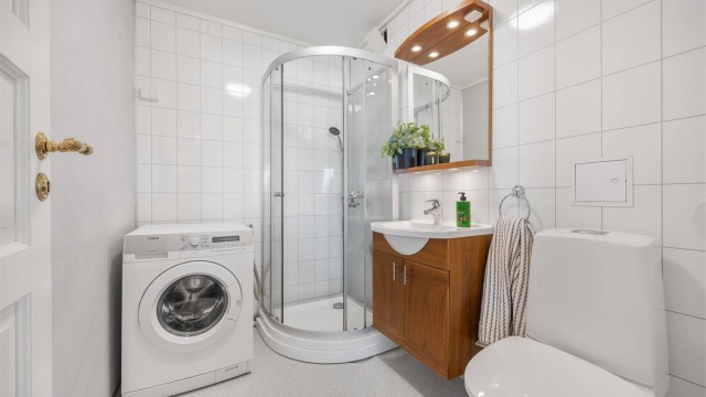 Bad i første etasje med dusjkabinett, toalett og opplegg for vaskemaskin.
