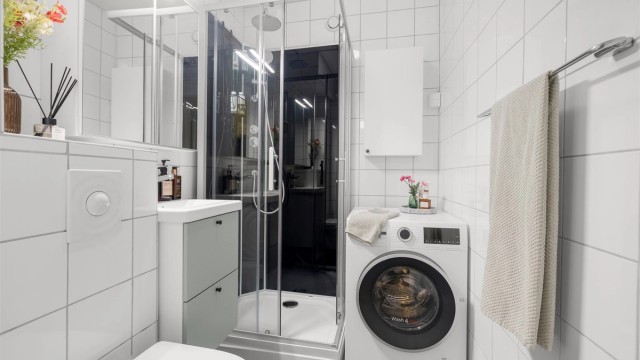 Badet har fliser på vegger og gulv, med komfortabel elektrisk gulvvarme. Her er det dusjkabinett og praktisk opplegg for vaskemaskin.