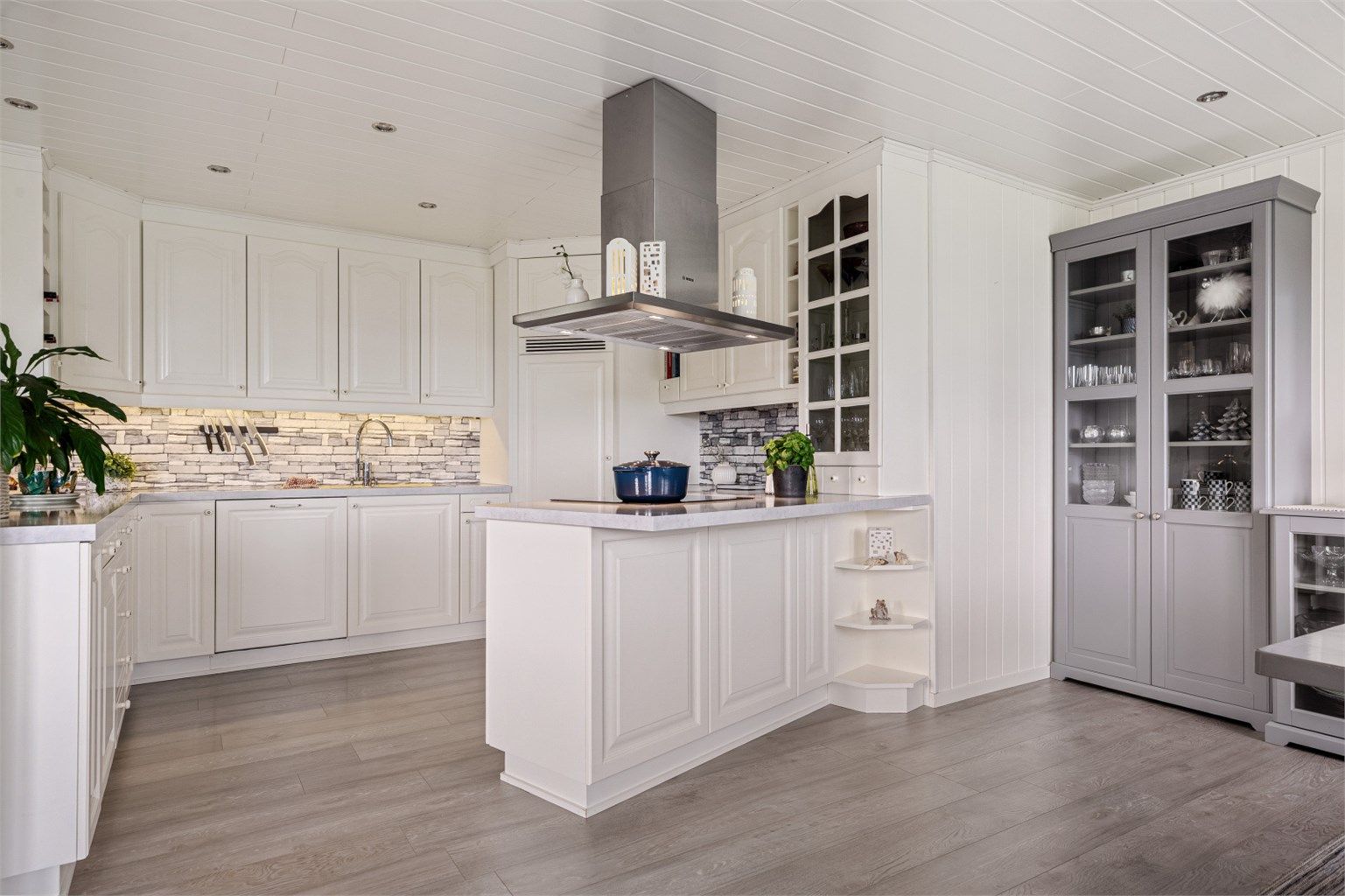 Pent kjøkken med lyse slette flater og flott benkeplate. 