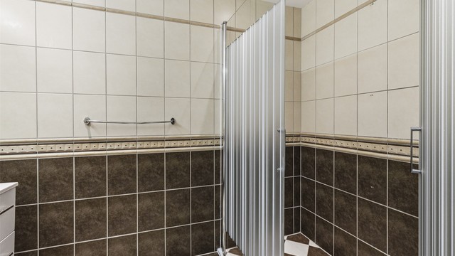 Badet har vegghengt servantinnredning, dobbel ovenpåliggende servant med armaturer, speil med overlys, stikkontakt over servant, dusjnisje med glassvegg og glassdør, samt vegghengt dusjarmatur (hånddusj og regndusj)