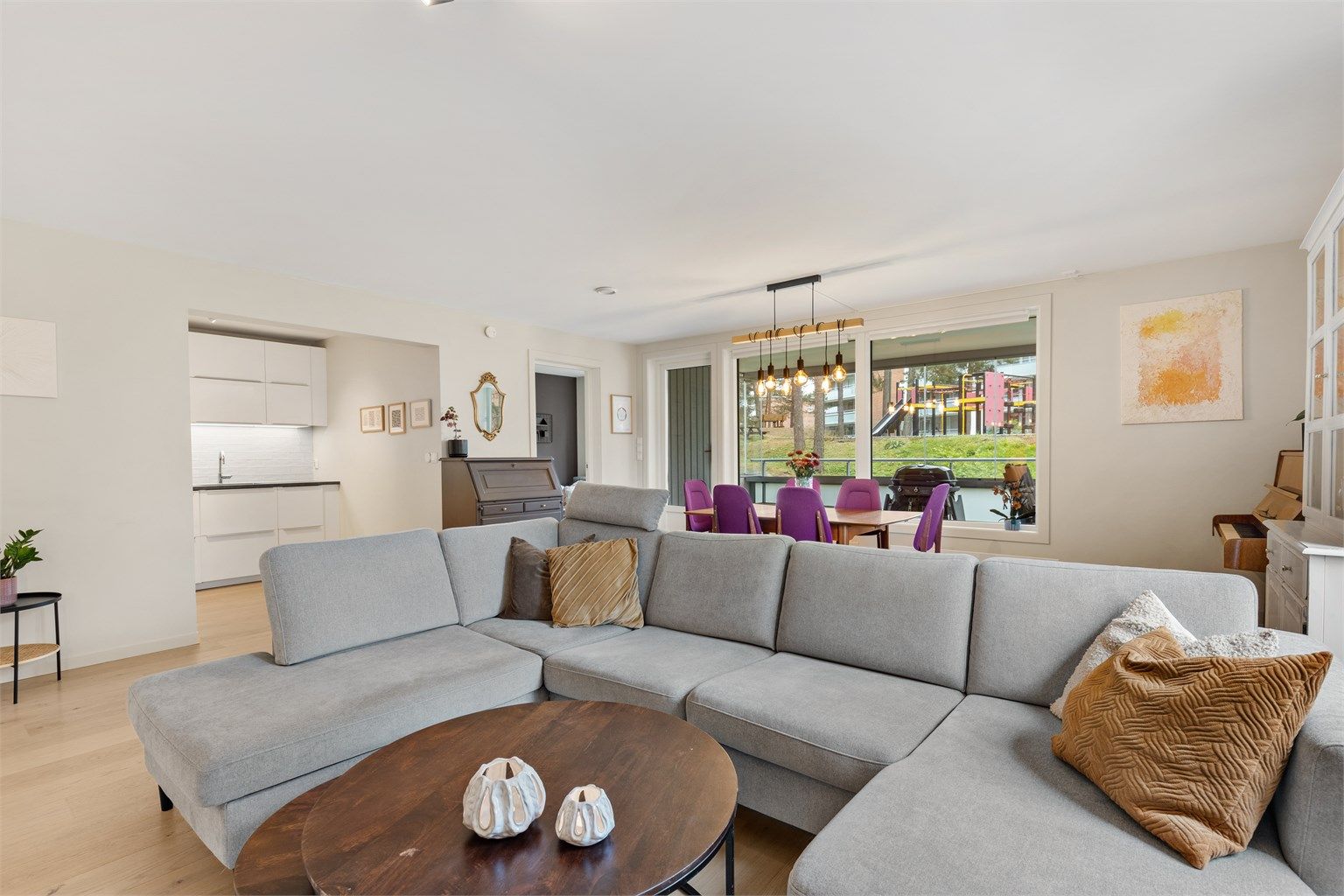 Kjøkkenet og stuen er holdt i en delvis åpen løsning, noe som skaper et naturlig og sosialt samlingspunkt i leiligheten. Her er også utgangen til boligens romslige balkong.