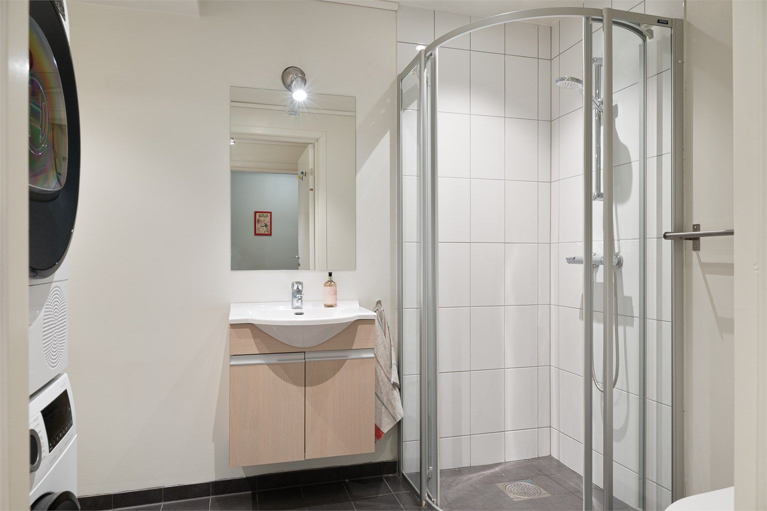 Innredet med dusjnisje, vask, wc og opplegg til vaskemaskin og kondenstørketrommel. Stor bod på innsiden av badet. 