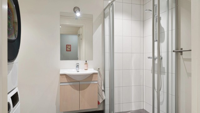 Innredet med dusjnisje, vask, wc og opplegg til vaskemaskin og kondenstørketrommel. Stor bod på innsiden av badet.