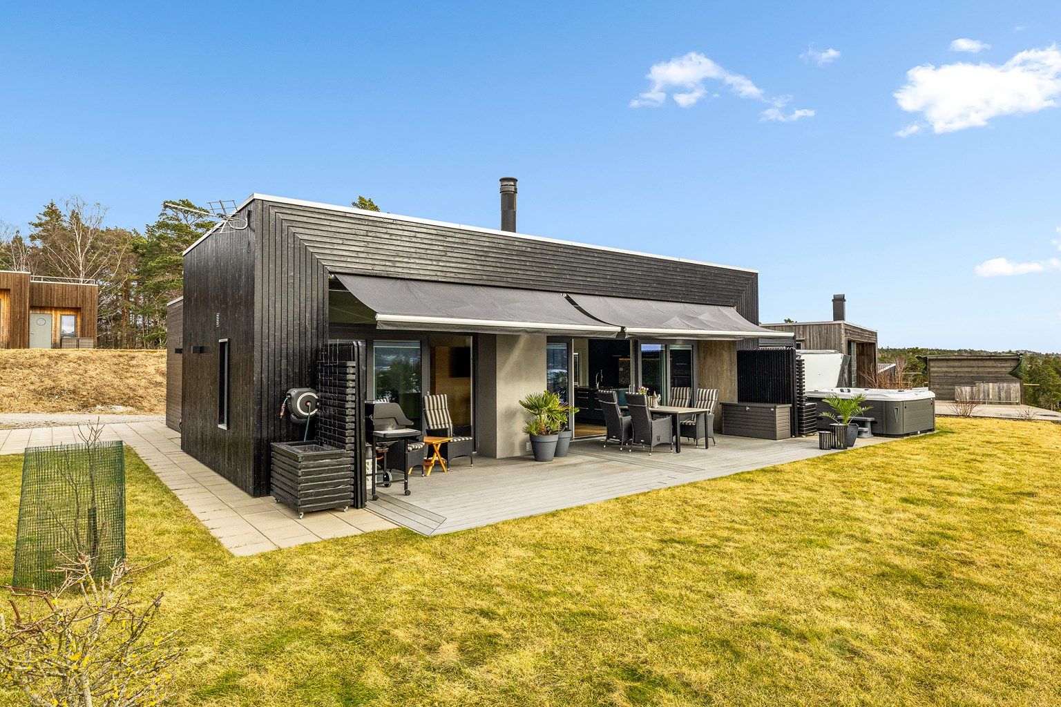 Store terrassemarkiser med elektrisk styring gir skygge på solfylte dager på terrassen.