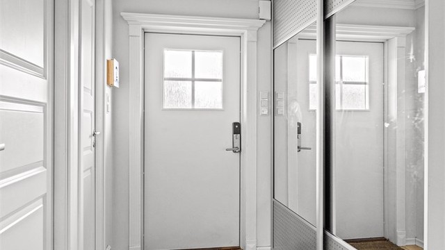 Entré med flislagt gulv og en romslig skyvedørsgarderobe med speilfronter.